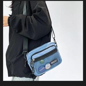 Blue nylon messenger bag featuring a front black mesh pocket and adjustable strap