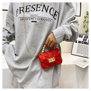 Close-up of red quilted mini jelly bag with pearl handle and golden chain on model