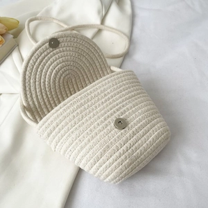 Gros plan du sac bandoulière tissé crème avec rabat rond et fermoir magnétique