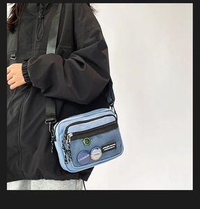 Detail of light blue canvas crossbody bag with mesh pocket and adjustable shoulder strap