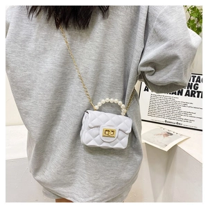 Detailed close-up of white quilted mini bag with pearl handle and golden chain strap