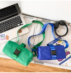 Detail view of nylon crossbody bags in bright green and blue with large buckle design
