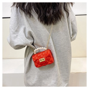 Detail view of mini red quilted jelly bag with pearl handle and gold chain strap