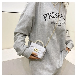 Detailed view of white quilted mini jelly bag featuring pearl handle and gold chain strap