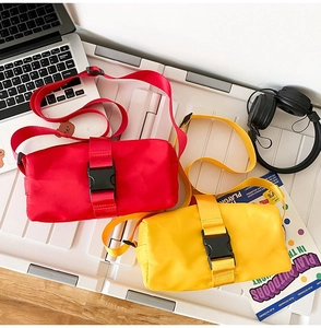 Detail view of red and yellow nylon crossbody bags with functional buckles on a desk