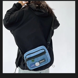 Detail of light blue nylon crossbody bag with mesh pockets and adjustable black strap