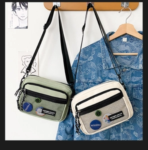 Detail of canvas messenger bag featuring a front mesh pocket and stylish brand patch