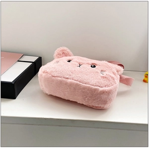 Detalle de cerca del bolso de peluche rosa con rasgos faciales bordados en negro