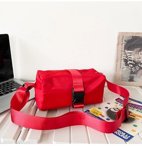 Macro detail of red Oxford nylon crossbody bag with wide strap and plastic buckle
