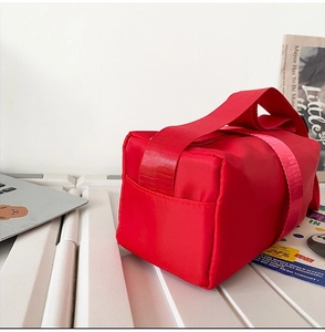 Detail view of a bright red nylon crossbody bag with durable woven handles for commute