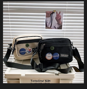 Detail of canvas messenger bag with mesh zipper pocket and decorative badges