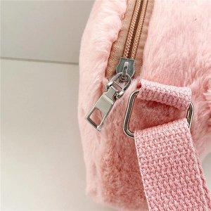 Detalle del bolso de felpa rosa con cremallera metálica plateada y correa de tela