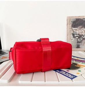 Detailed bottom view of a red nylon crossbody bag with durable straps and plastic buckle