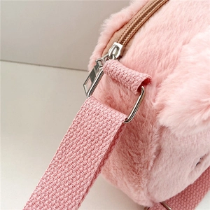 Detalle del bolso de felpa rosa con cremallera metálica plateada y correa de nailon