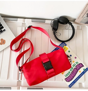 Detail view of red oxford fabric crossbody bag with black buckle and outdoor accessories