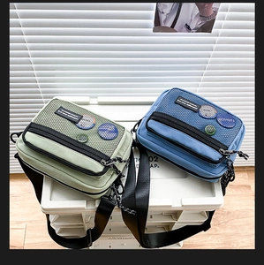 Detail view of retro canvas crossbody bags in mint green and royal blue with mesh pockets