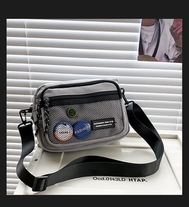 Detail of grey canvas crossbody bag with mesh pocket and black nylon shoulder strap