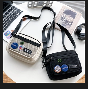 Detail view of canvas crossbody bags with front mesh pocket and fashion badge