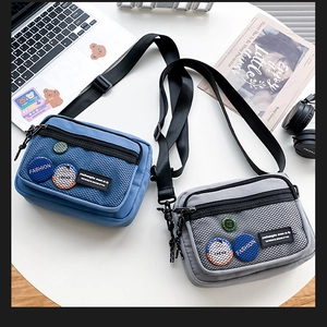 Close-up of casual canvas crossbody bags with mesh pockets and colorful badges on table