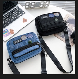 Detail of square canvas messenger bags with mesh pocket and colorful badges decorations