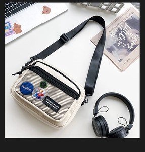 Detail view of canvas crossbody bag with black mesh pocket and stylish patches