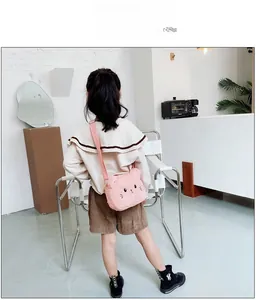 Bolso bandolera de peluche rosa con forma de gato mostrado por una modelo infantil