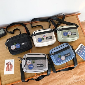 Collection of small canvas crossbody bags in five colors with mesh pockets and adjustable straps