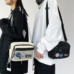Detail of canvas messenger bags in black and white with mesh pocket and fashion logo