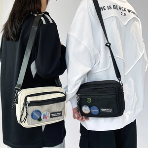 Detail showing canvas messenger bags with grid pockets and decorative embroidery patches