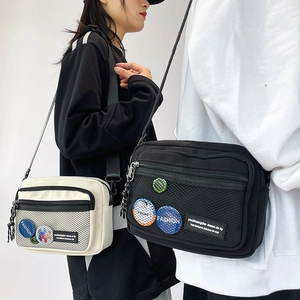 Detail of canvas messenger bag featuring mesh pocket and decorative brand patches