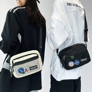 Detail of canvas messenger bags with mesh pocket and fashion badges in black and white