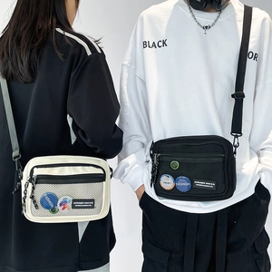 Detail of canvas messenger bag with mesh pocket and colorful badges in a urban style