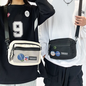 Detailed view of canvas crossbody bags featuring mesh pockets and colorful badges