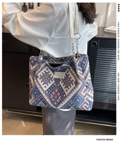 Detail of colorful geometric woven tote bag featuring metallic chain and leather shoulder strap