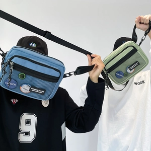 Detail of blue and green canvas messenger bags with mesh zip pockets and fashion patches