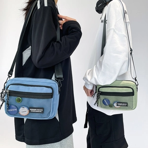 Detail of blue and green canvas messenger bags with mesh pockets and adjustable straps