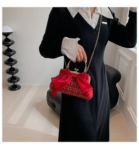 Détail d'un sac en tweed rouge avec un grand nœud en satin et une poignée dorée