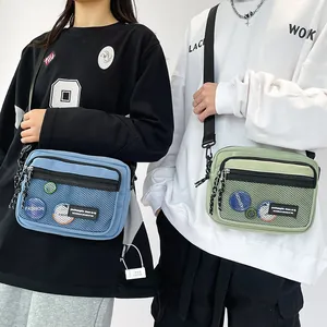 Detail of canvas messenger bags in blue and green with mesh pockets and badges