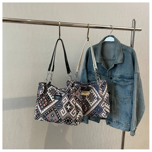 Detail of geometric pattern woven tote bag with metallic chain and leather handles