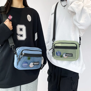 Detail showing two casual canvas cross-body bags in blue and green with mesh pockets