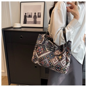 Close-up of geometric woven tote bag with silver chain detail and black leather strap