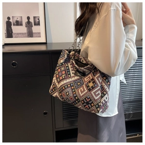 Detail of colorful woven tote bag with metallic chain strap and fashion label