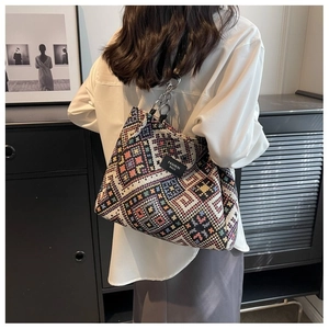 Detail of colorful geometric woven tote bag with silver chain strap and fashion label