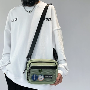 Detail of light green canvas crossbody bag featuring a mesh pocket and adjustable strap