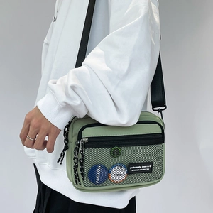 Detail view of light green casual crossbody bag with black mesh pocket and nylon texture