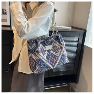 Detail of colorful geometric woven tote bag with silver chain strap and leather label
