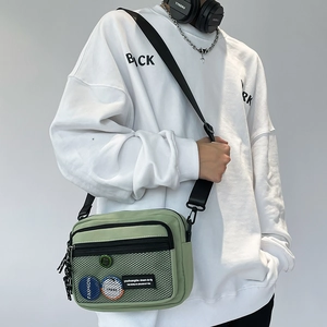 Detail view of green canvas messenger bag with mesh pockets and adjustable black strap