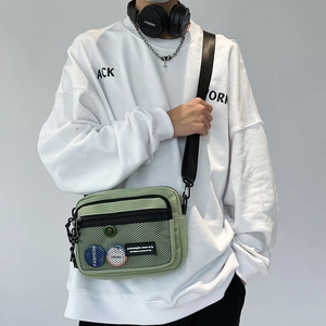Detail of light green canvas messenger bag featuring mesh pockets and adjustable strap