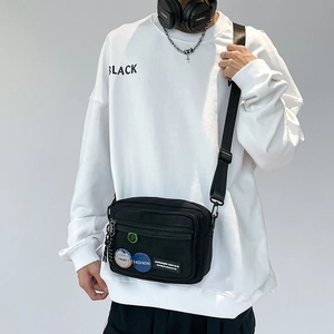 Detail of black sports crossbody bag with mesh front pocket and fashion badges