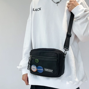 Detail of black canvas messenger bag with mesh pocket and trendy fashion patch labels
